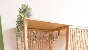 A wooden shelving unit with three shelves, a plant on the top shelf, and a candle holder on the middle shelf. - Premium Business Apartment (Vienna)