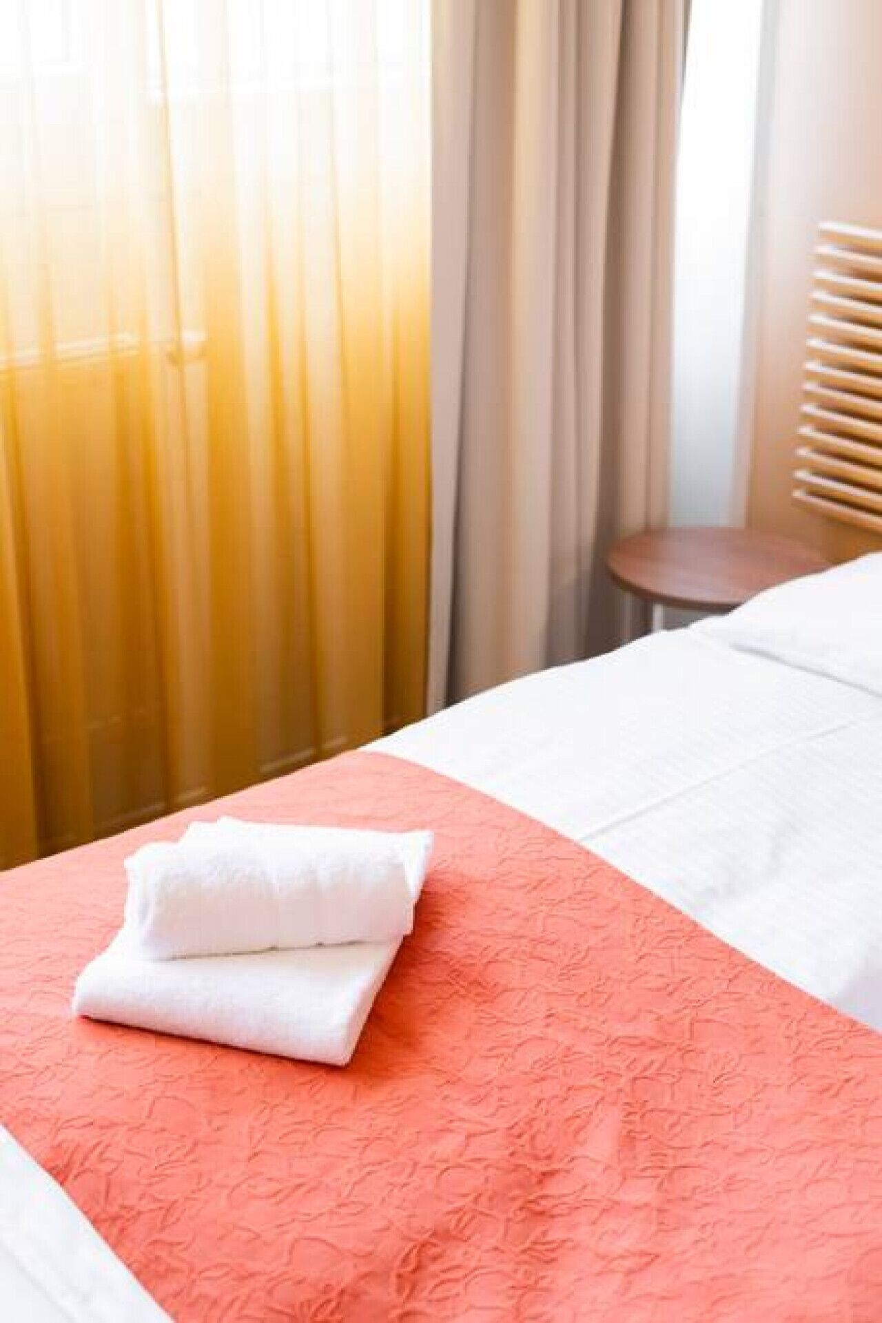 A hotel room with a bed, a chair, and a window with curtains.