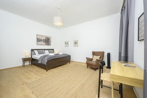 A bedroom with a bed, bedside tables, a chair, a desk, and a hanging light fixture. - Small Business Suite Mariahilf (Vienna)