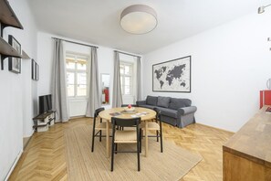 En moderne stue med et rundt spisebord, en grå sofa og et verdenskort på væggen.