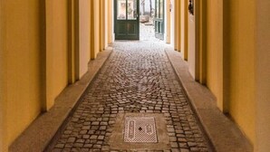 Ein Korridor mit einem Kopfsteinpflasterboden und einer grünen Tür am Ende.