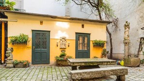 Ein Innenhof mit einer Steinsitzbank, zwei verzierten Doppeltüren und einer Statue.