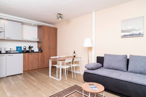 Un appartement moderne comprenant un coin cuisine, un espace repas, un canapé et une petite table.