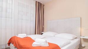 A hotel room with a bed, white bedding, an orange throw blanket, and a headboard. - Apartment Favoriten top 1 (Vienna)