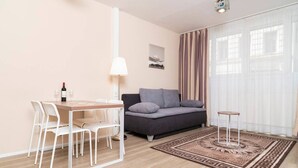 A modern living room with a sofa, a dining table with chairs, a lamp, and a patterned rug. - Apartment Favoriten top 1 (Vienna)