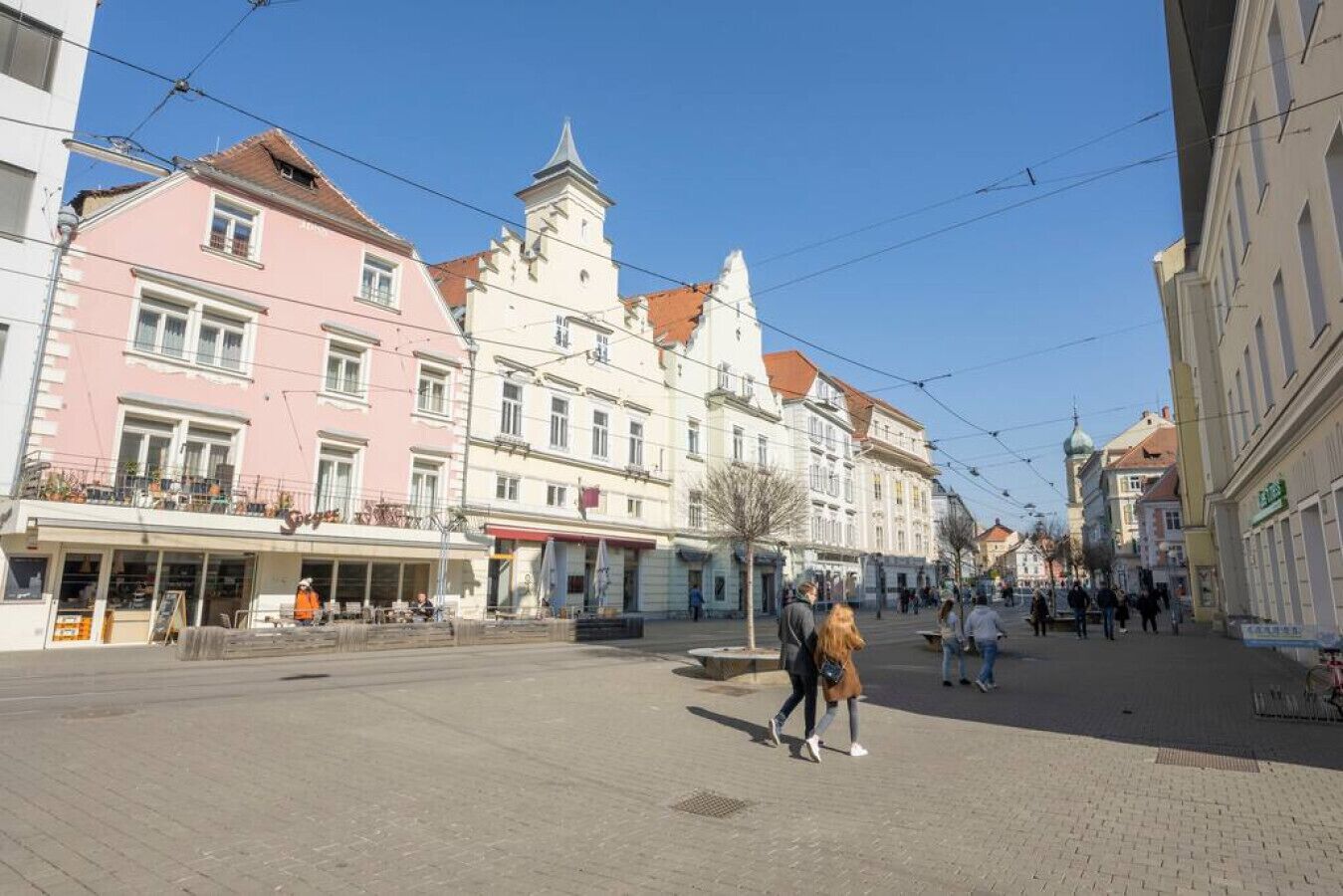 A pedestrian street with buildings, some with balconies and shops.