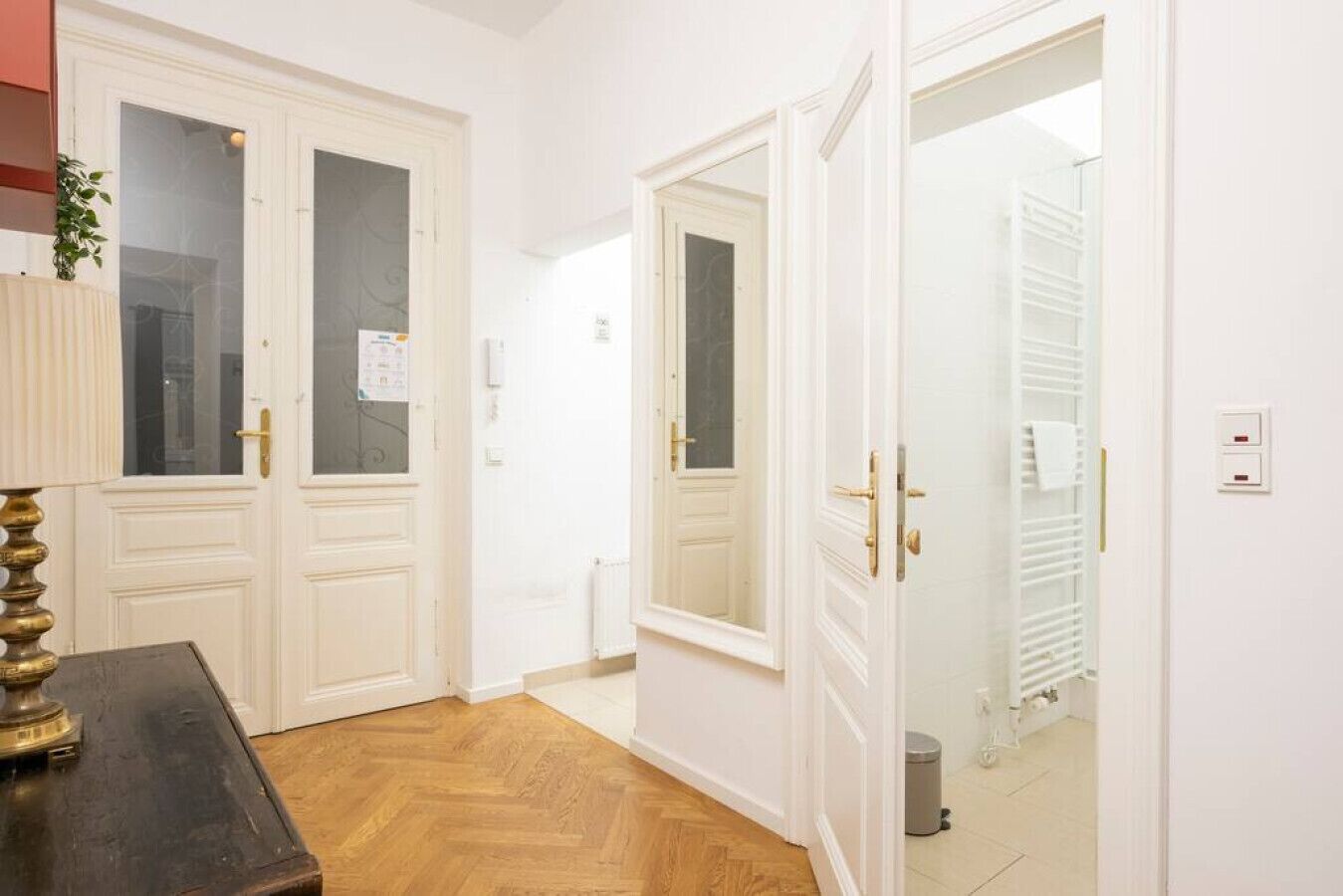 A hallway with white doors, a radiator, and a trash bin.