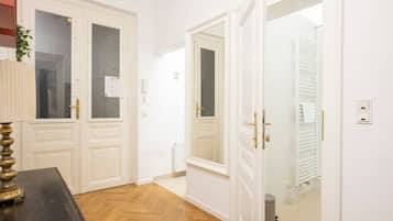 A hallway with white doors, a radiator, and a trash bin.