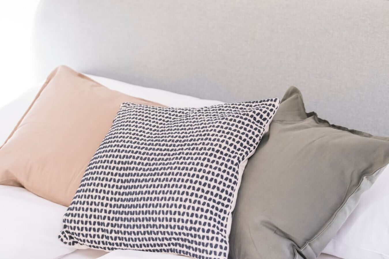 Un lit avec trois oreillers aux motifs et aux couleurs différents.