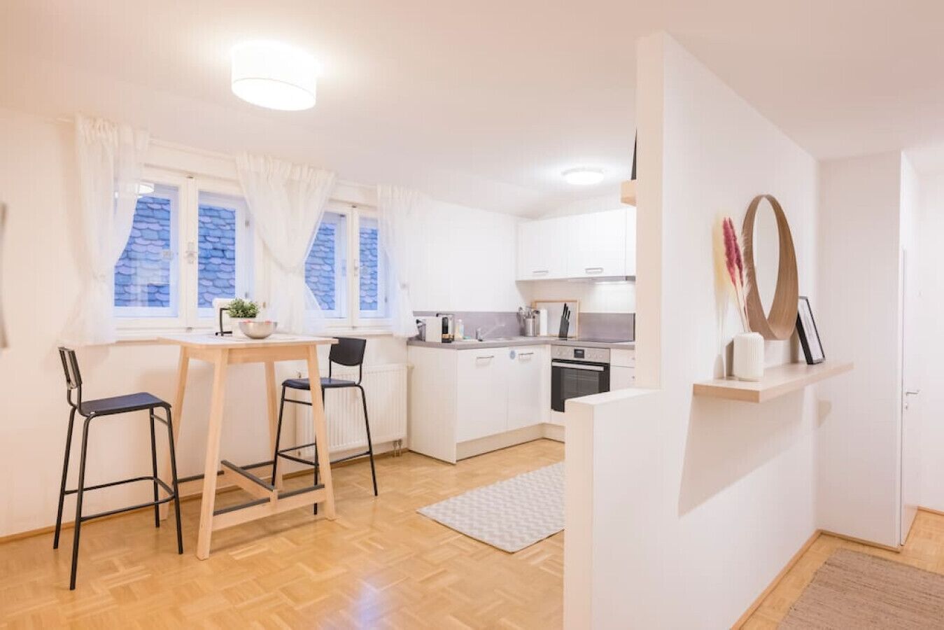 Eine moderne Küche mit weißen Schränken, einem Holztisch und zwei Stühlen.
