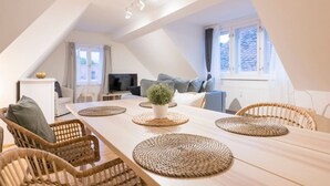 Um espaço de estar moderno estilo loft, com área de refeições, assentos e uma televisão.