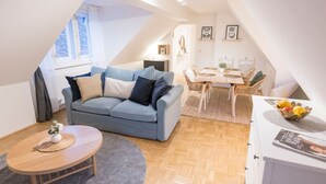 Um apartamento loft aconchegante com um sofá azul, uma mesa de jantar e uma pequena cozinha.