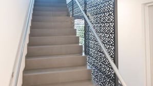 A staircase with a patterned glass barrier, a handrail, and an exit sign. - Ottakring Balcony Suite (Vienna)