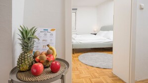 A room with a bed, a small table with fruits, and a welcome sign. - Zum Grazer Uhrturm in Graz Austria (Graz)