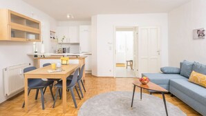 Eine moderne Wohnung mit Essbereich, Küchenzeile und Wohnzimmer mit Sofa und Couchtisch.