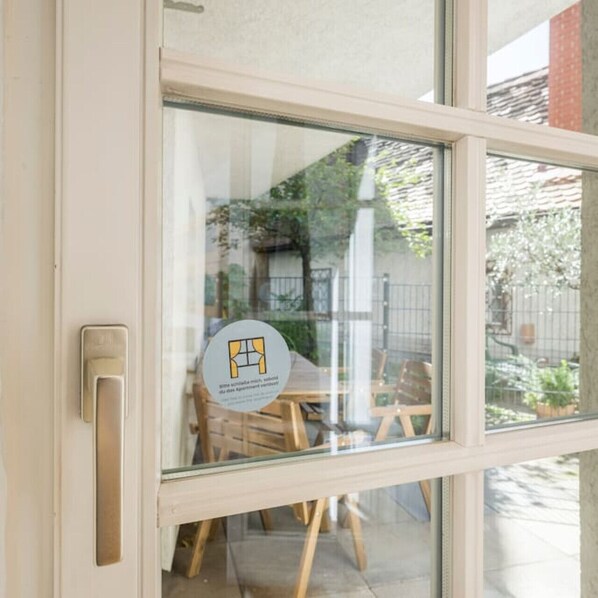 A window with a view of a wooden table and chairs outside, a door with a handle, and a glass pane reflecting the outside scene.