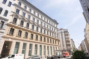 Ein mehrgeschossiges Gebäude im klassischen Stil, mit einer symmetrischen Fassade, gleichmäßig angeordneten Fenstern und dekorativen Stuckverzierungen.