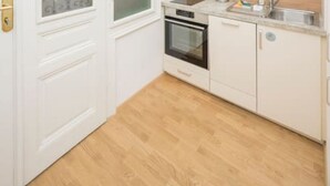 A compact kitchen with white cabinets, a microwave, an oven, and a sink. - Best of Hernals Top 24 (Vienna)