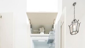 A compact kitchen with a built-in refrigerator, a microwave, and a coffee maker on a small cabinet. - Best of Hernals Top 24 (Vienna)