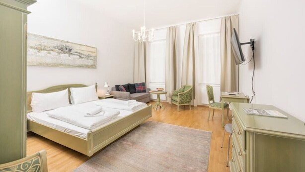 A hotel room with a bed, a desk, a chair, a television, and a painting on the wall. - Best of Hernals Top 30 (Vienna)