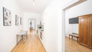 A bright, modern kitchen with white cabinets, a dining area with a table and chairs, and a hallway leading to a living space. - Best of Hernals Top 34 (Vienna)