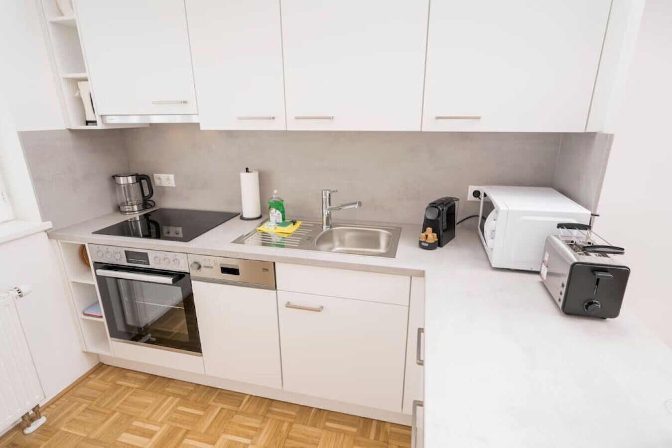 Eine kleine Küche mit Spülmaschine, Backofen, Spüle und Toaster.