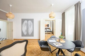 A modern hotel room with a dining area, a large abstract painting, and a view into the adjacent bedroom. - Central Business Apartment (Vienna)