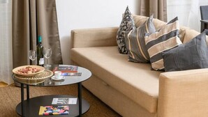 Un salon chaleureux avec un canapé beige, une table basse et un tableau représentant un coucher de soleil.