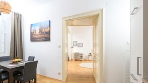 Une pièce moderne comprenant une table à manger, des chaises, une petite table avec un fauteuil, un tableau au mur et une porte donnant sur une autre pièce.
