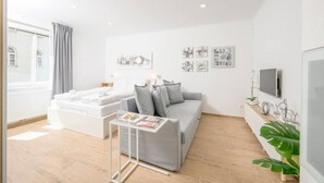 Un salon moderne avec un canapé gris, une table basse blanche et des œuvres d’art accrochées au mur.