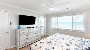 Ein Schlafzimmer mit Bett, Kommode, Fernseher und einem Fenster mit Jalousien.