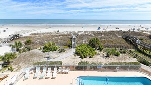 Ein Strandresort mit Pool, Liegestühlen und einer Holzterrasse.