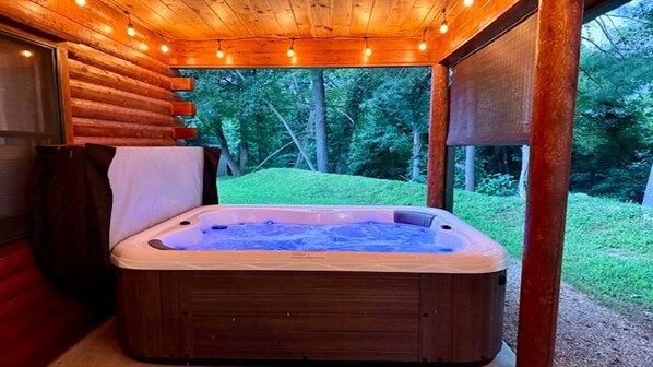 Un jacuzzi en una cabaña de madera con vistas a un paisaje verde.