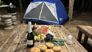 A camping setup with a tent, picnic table, wine bottle, and food. - Recanto das Videiras (Itapira)