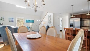 A modern kitchen with a wooden dining table, chairs, and a chandelier. - Wonderful dog friendly rental with access path to a private beach deeded at White's Pond! (Chatham)