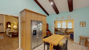 A spacious living area with a wooden dining table, a kitchen with a built-in refrigerator, and a cozy seating area with a sofa and chairs.