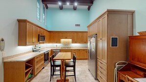A kitchen with wooden cabinets, a stainless steel refrigerator, a microwave, and a dining table with chairs.