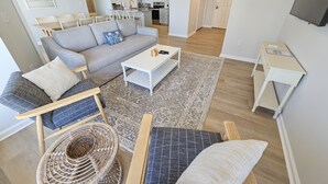 A modern living room with a grey sofa, a white coffee table, and a wicker chair.