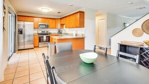 A modern kitchen with wooden cabinets, stainless steel appliances, and a dining area with a large table and chairs. - 4 Mi to Busch Gardens: Lovely Tampa Home! (Tampa)