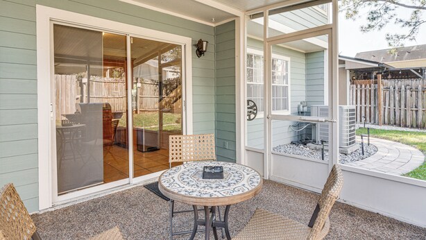 A covered patio with a round table and chairs, sliding glass doors leading to a backyard, and a view of a wooden fence. - 4 Mi to Busch Gardens: Lovely Tampa Home! (Tampa)