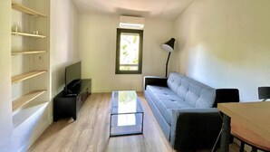 A compact living space with a sofa, a coffee table, a TV, and a window.