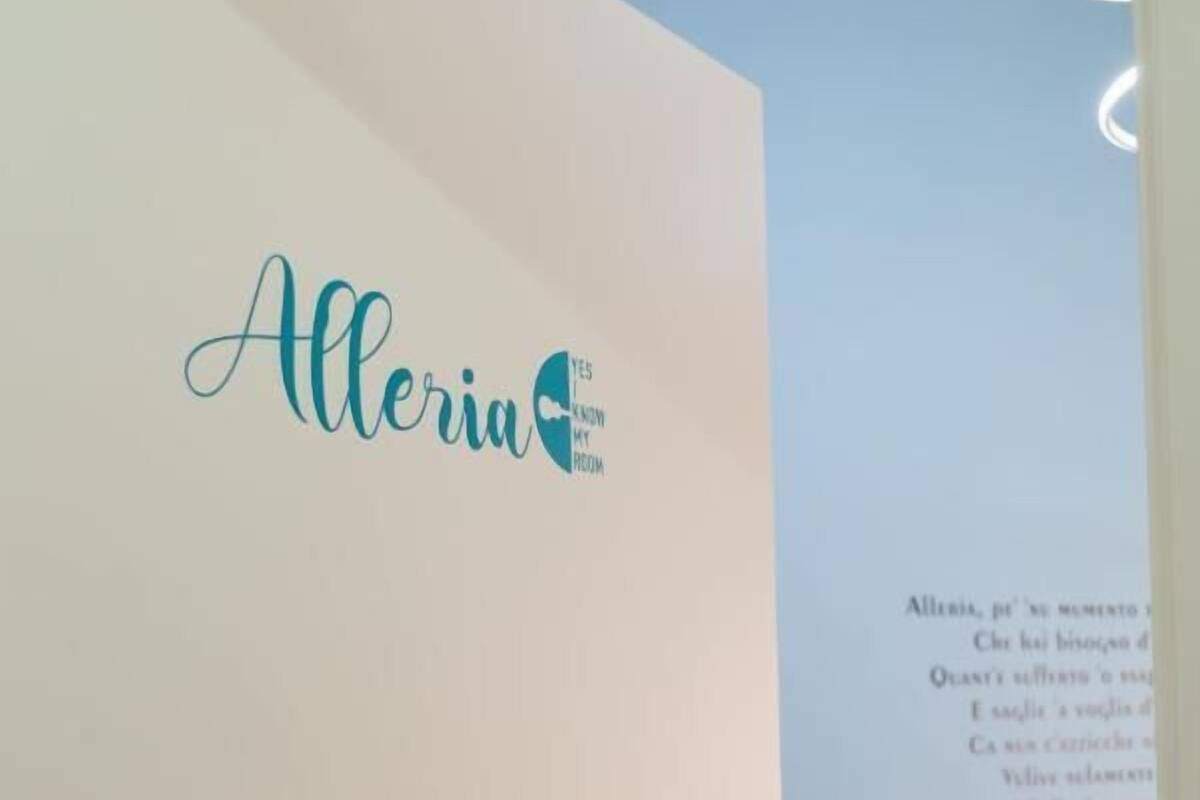 Ein Zimmer mit einer Tür, auf der 'Alleria' steht, und einem Bett mit weißer Bettdecke.