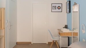 Quarto com cama, escrivaninha, cadeira, guarda-roupa e luminária de teto.