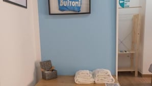 Um quarto com escrivaninha, cadeira, camisa de jogo emoldurada, cesto pequeno e armário branco.