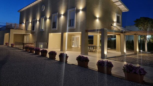 A two-story house with a covered patio area, multiple windows, and a well-lit entrance. - Ro agrimaison  (Volla)