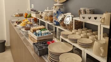 A buffet area with a wooden clock, various food items, and stacked plates and bowls.