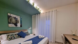 A neatly made bed with blue and white bedding, a headboard, and a wall-mounted artwork. - Ro agrimaison  (Volla)