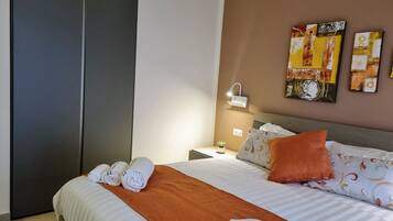 Ein ordentlich gemachtes Bett mit aufgerollten Handtüchern, einer braunen Tagesdecke und gemusterten Kissen.
