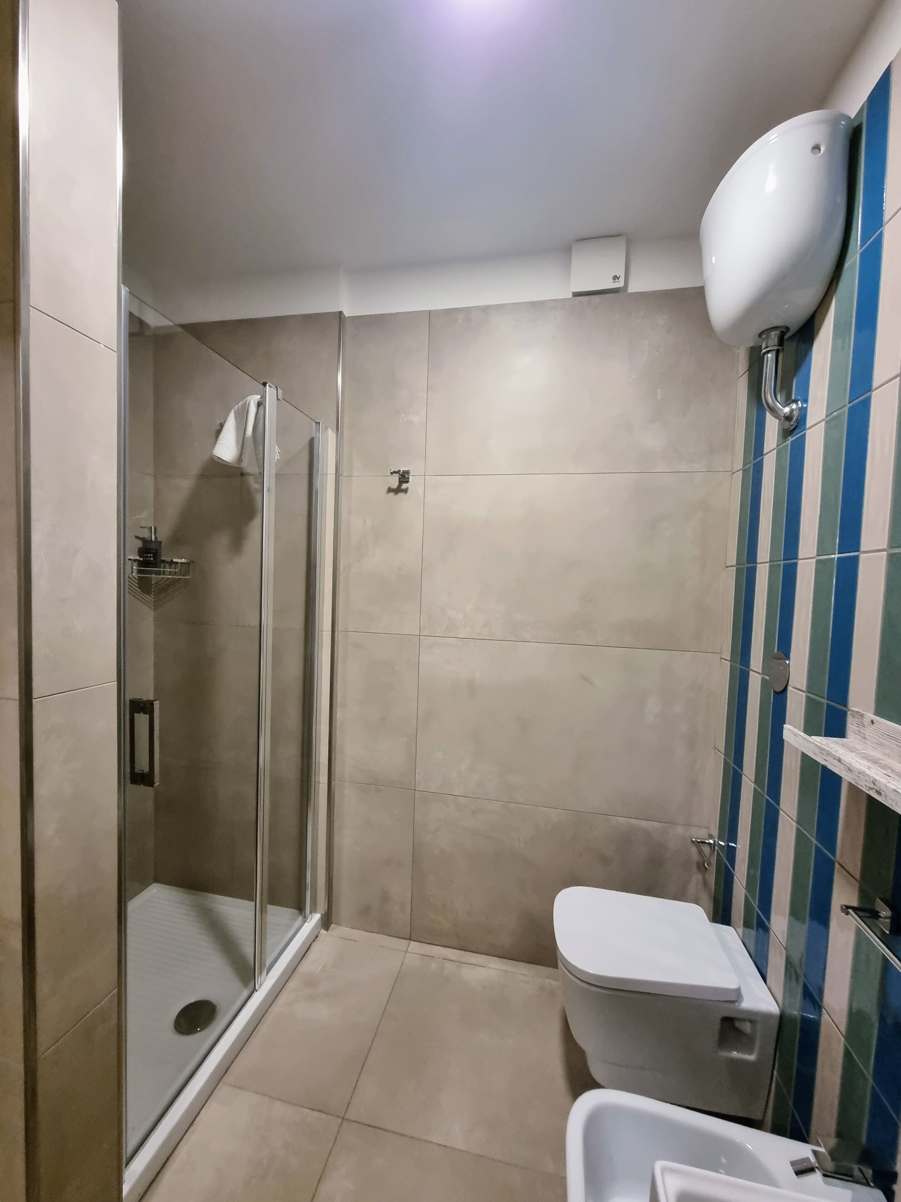 A bathroom with a glass-enclosed shower, a toilet, and a sink.