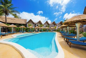 Una piscina al aire libre, sombrillas, sillones reclinables de piscina
